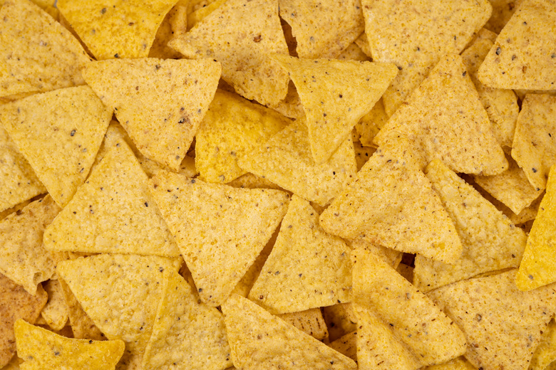Background of Corn Tortilla Chips or Nachos. Tasty Mexican nachos chips as background, closeup